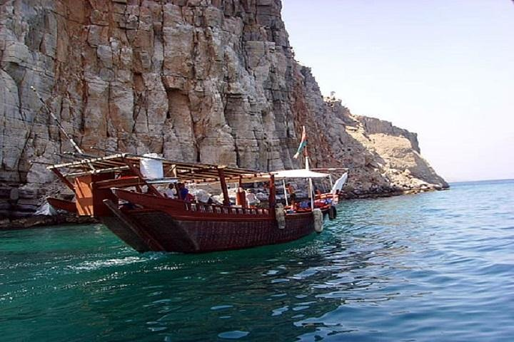 Experience the stunning Musandam Fjords aboard a traditional Dhow exploring crystal-clear waters and majestic cliffs while enjoying a day of relaxation and scenic beauty.